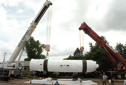 Two cranes working together to lift the pressurizer into the rail car